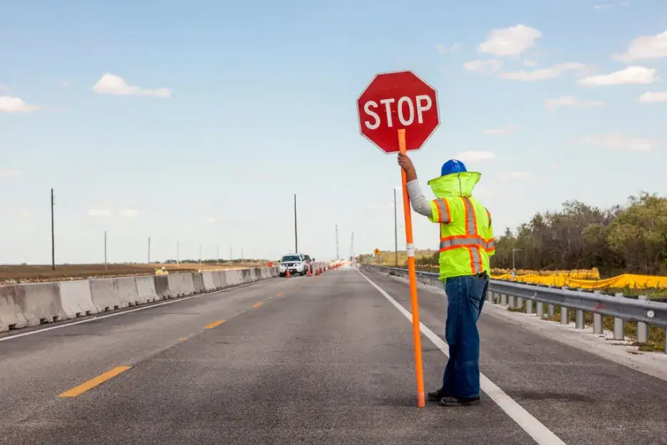 C31 contractor controlling the flow of traffic using a STOP/SLOW paddle.